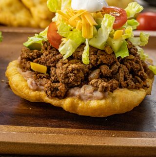 fry bread topped with beans, meat, lettuce, cheese and sour cream
