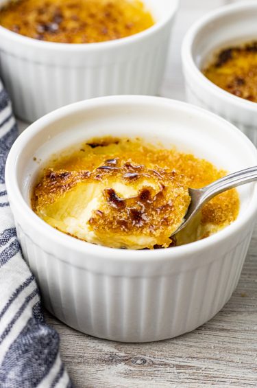 spoonful of creme brulee from a small white ramekin