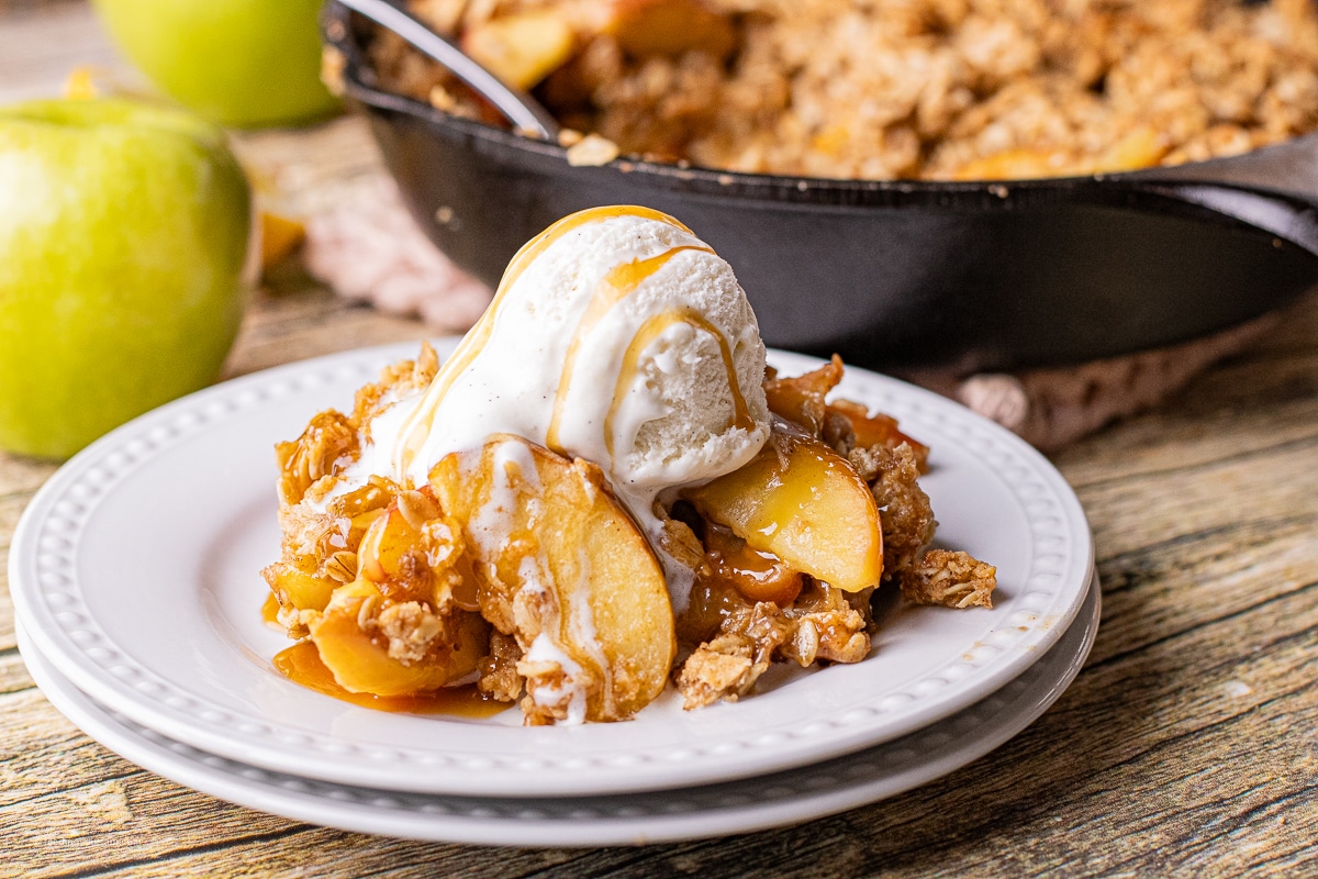 apple crisp with an oat topping topped with ice cream and caramel sauce