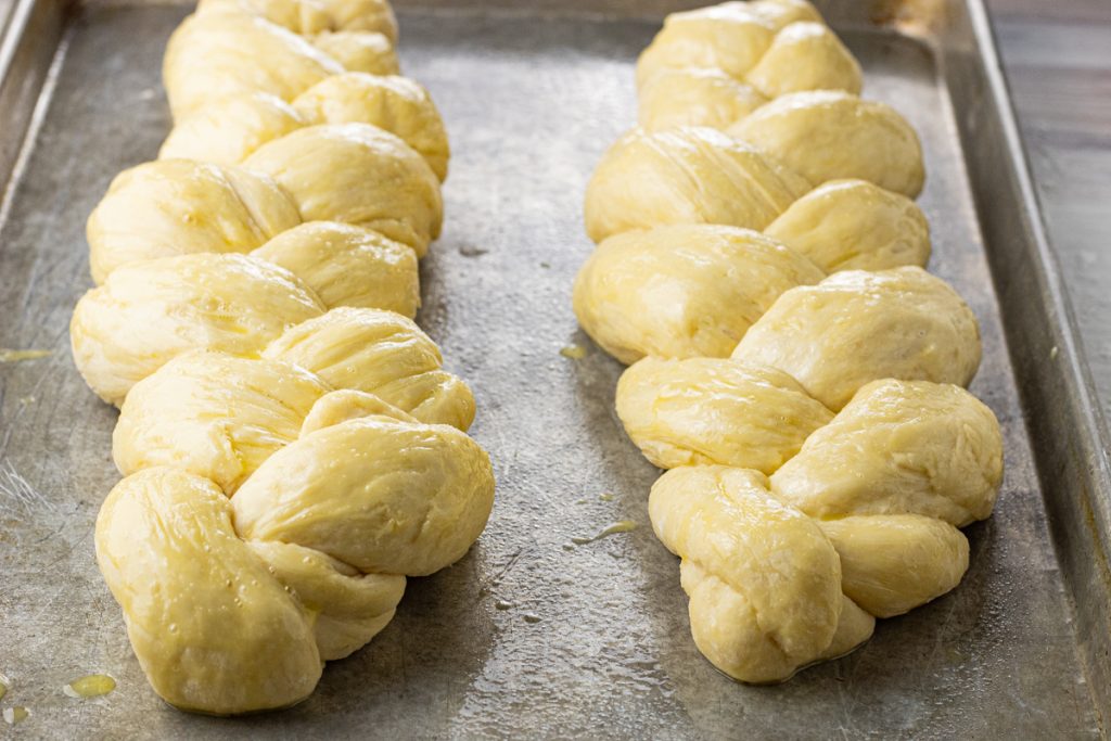 two loaves of braided bread dough on a baking sheet
