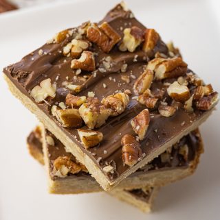 stacked shortbread bars topped with chocolate and pecans