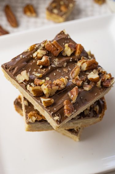 stacked shortbread bars topped with chocolate and pecans