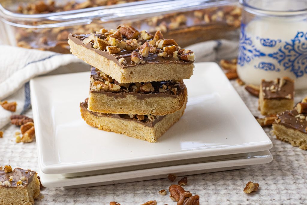 stack of shortbread bars that have been topped milk chocolate and pecans