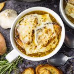 bowl of french onion soup topped with Swiss cheese and crusty bread
