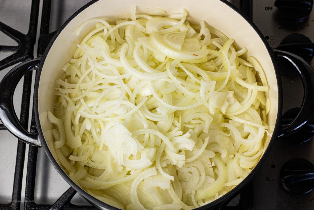 sliced yellow onions in a big black pot