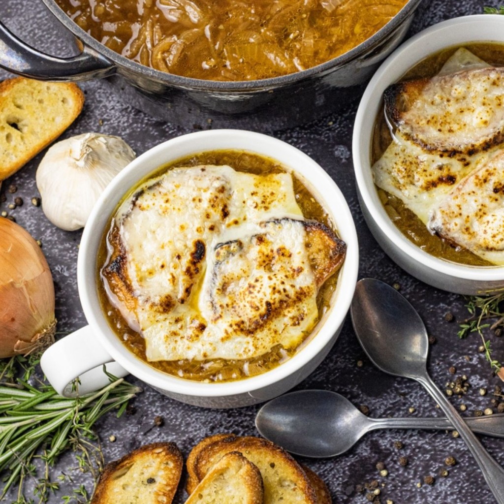white bowl of onion soup topped with swiss cheese and bread slices