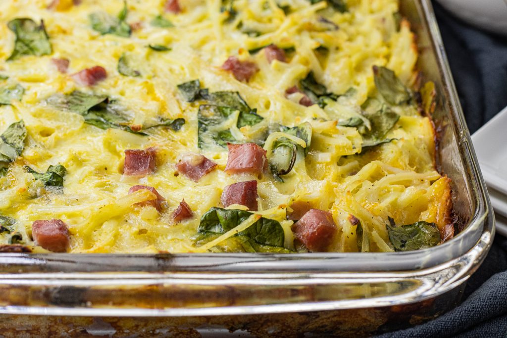 egg, ham, spinach, cheese, hash brown casserole in a glass baking dish