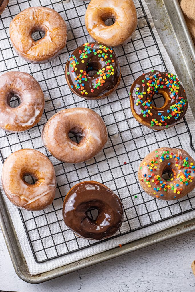 chocolate glazed donuts with sprinkles and glazed donuts on a cooling rack