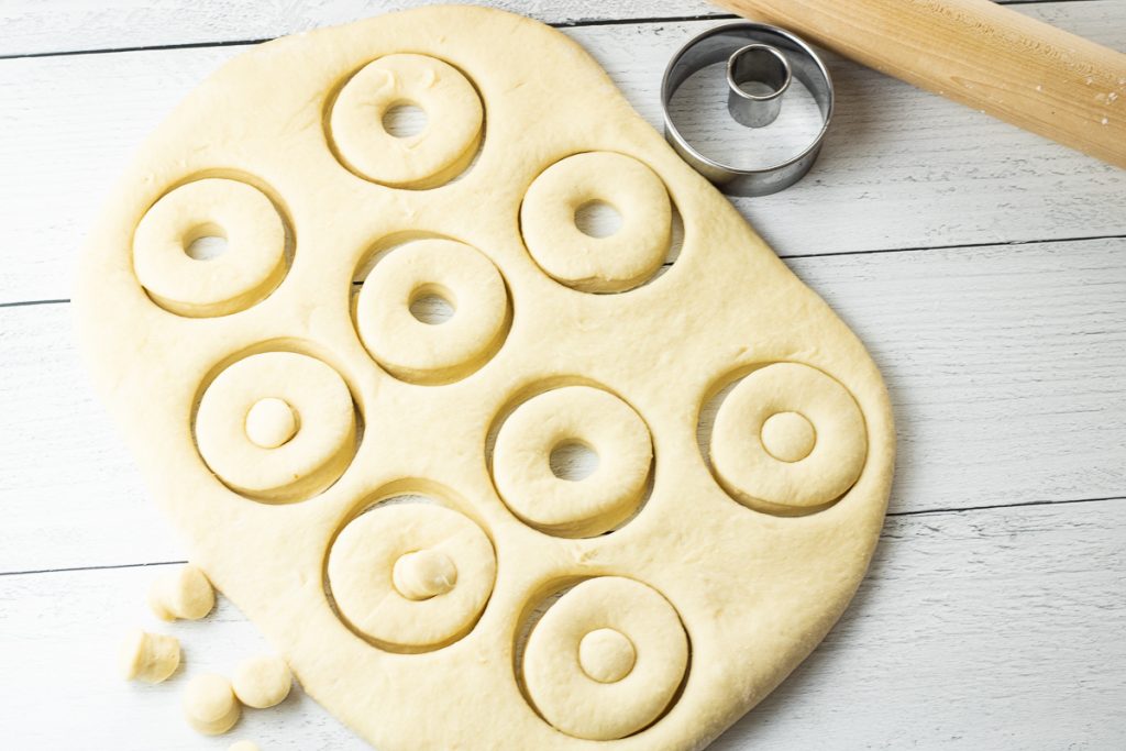 donut dough rolled out with cut out donut shapes