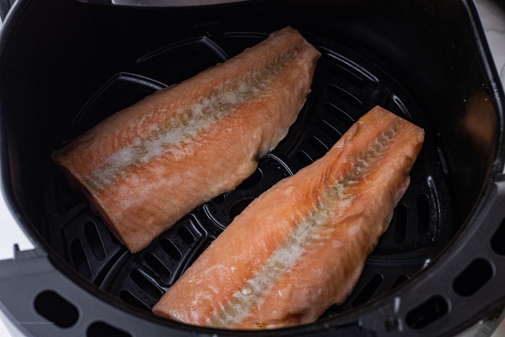 frozen salmon filets in the basket of an air fryer