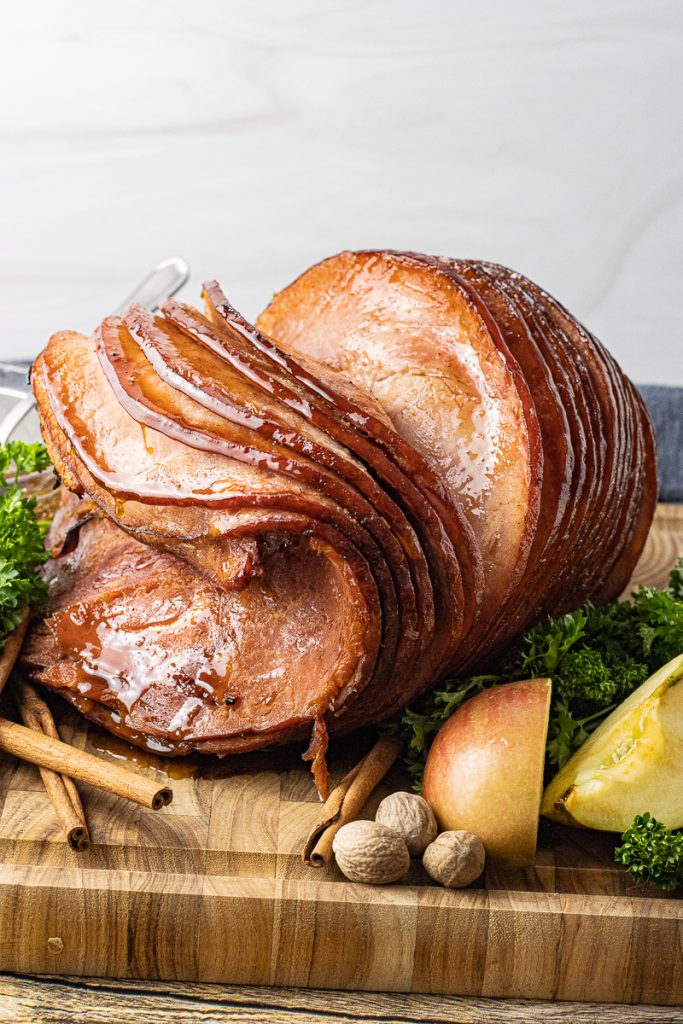 glazed, sliced ham on a wooden cutting board