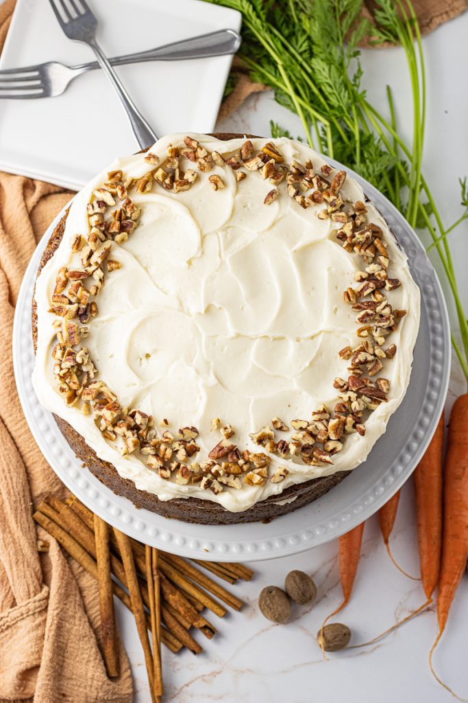 carrot cake frosted with cream cheese and topped with crushed pecans