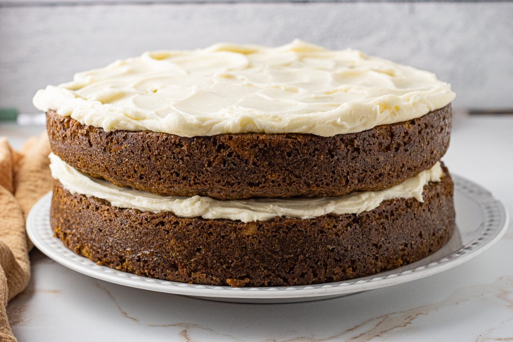 two carrot cake rounds on top of each other with cream cheese frosting