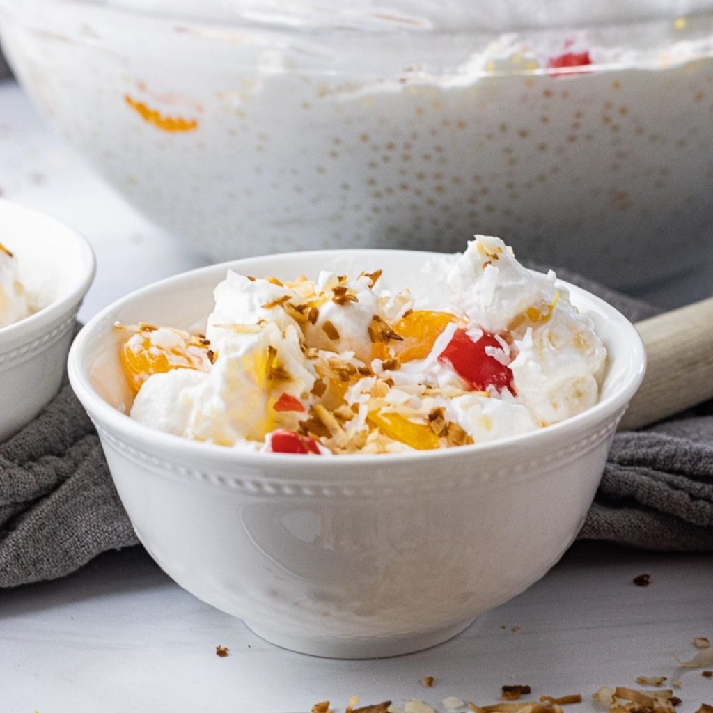 white bowl filled with fruit salad topped with toasted coconut