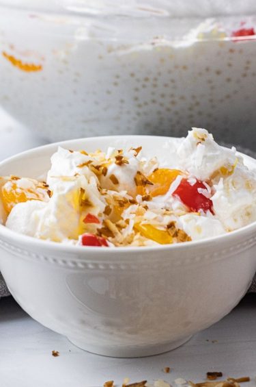 white bowl filled with fruit salad topped with toasted coconut