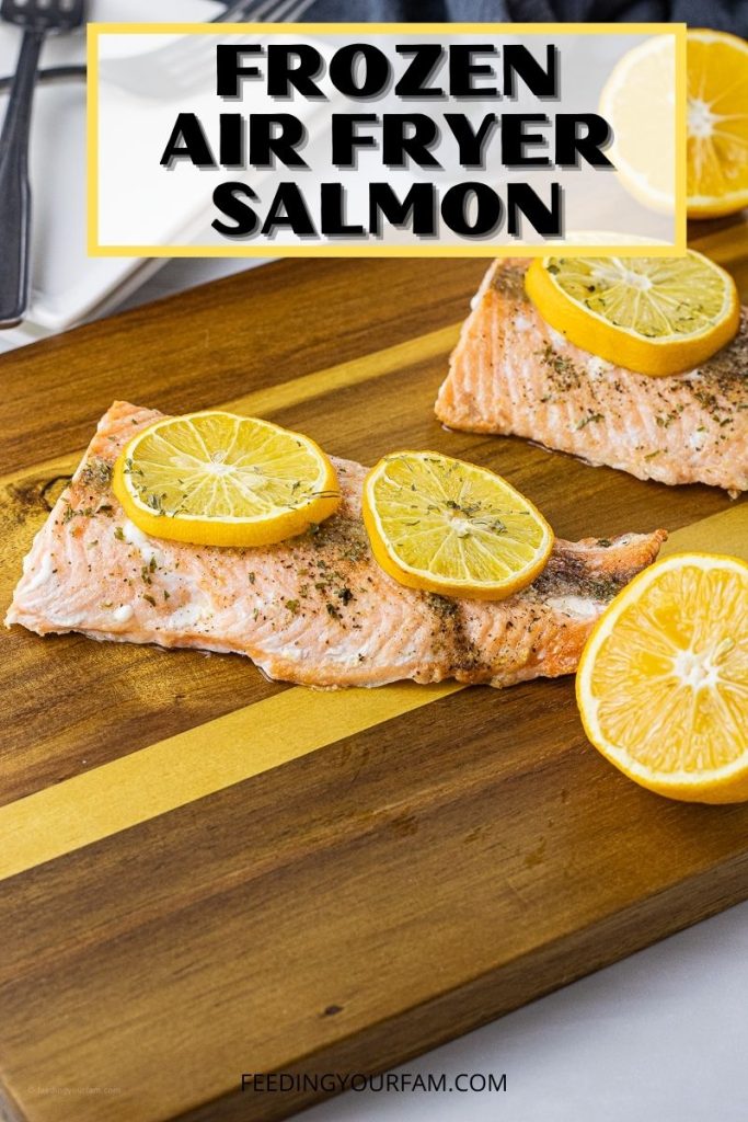 cooked salmon filets on a wooden cutting board topped with lemon slices