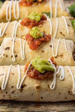 baked chimichangas topped with salsa, guacamole and sour cream