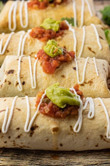 baked chimichangas topped with salsa, guacamole and sour cream