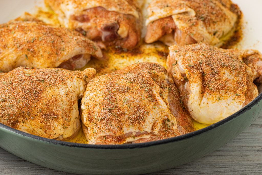seasoned, uncooked chicken thighs in a round pan