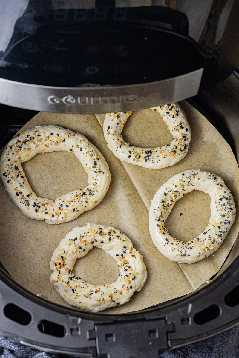 uncooked bagels in an air fryer basket