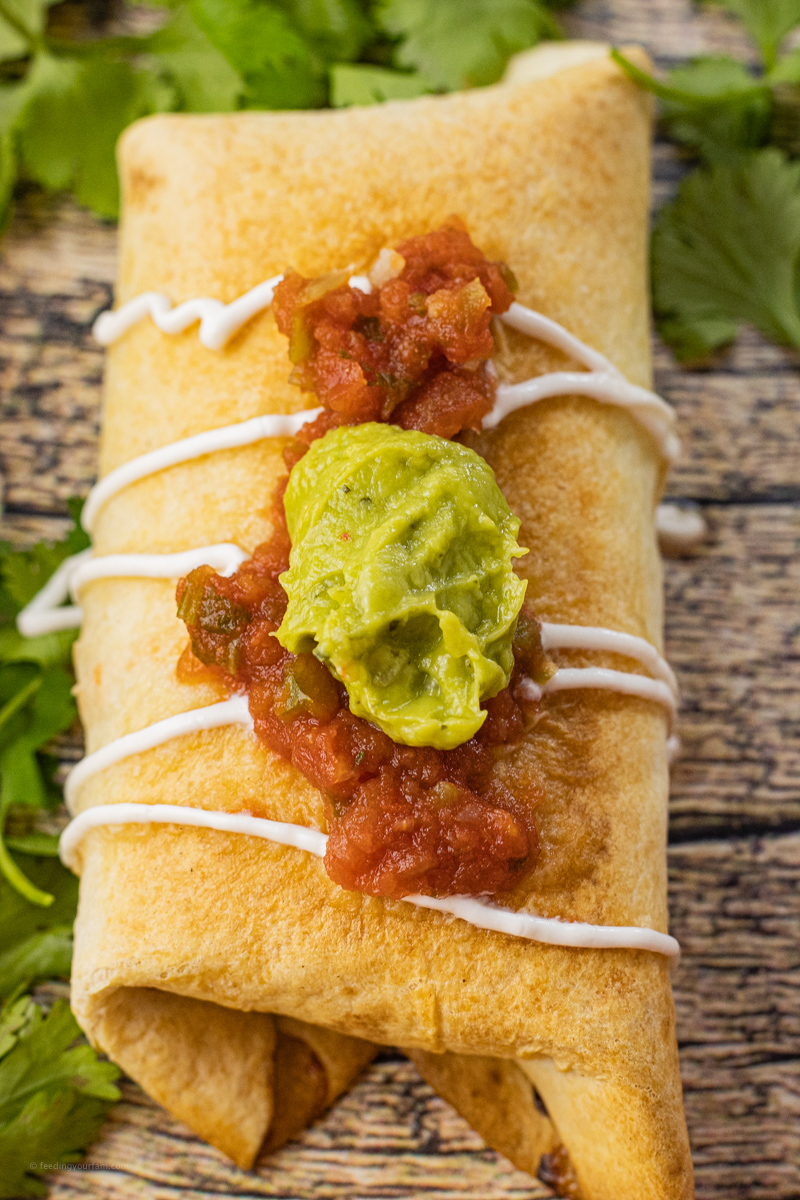 golden brown chimichanga topped with salsa and guacamole
