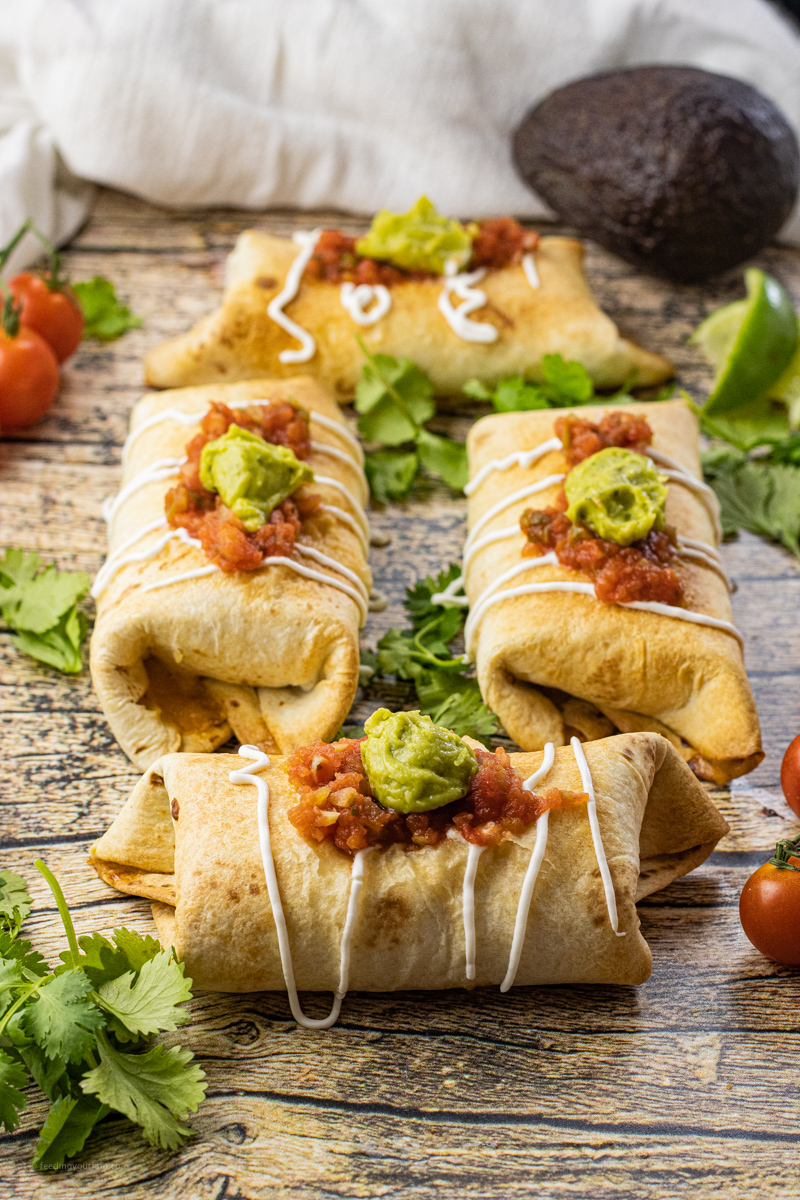 browned chimichangas topped with salsa and guacamole