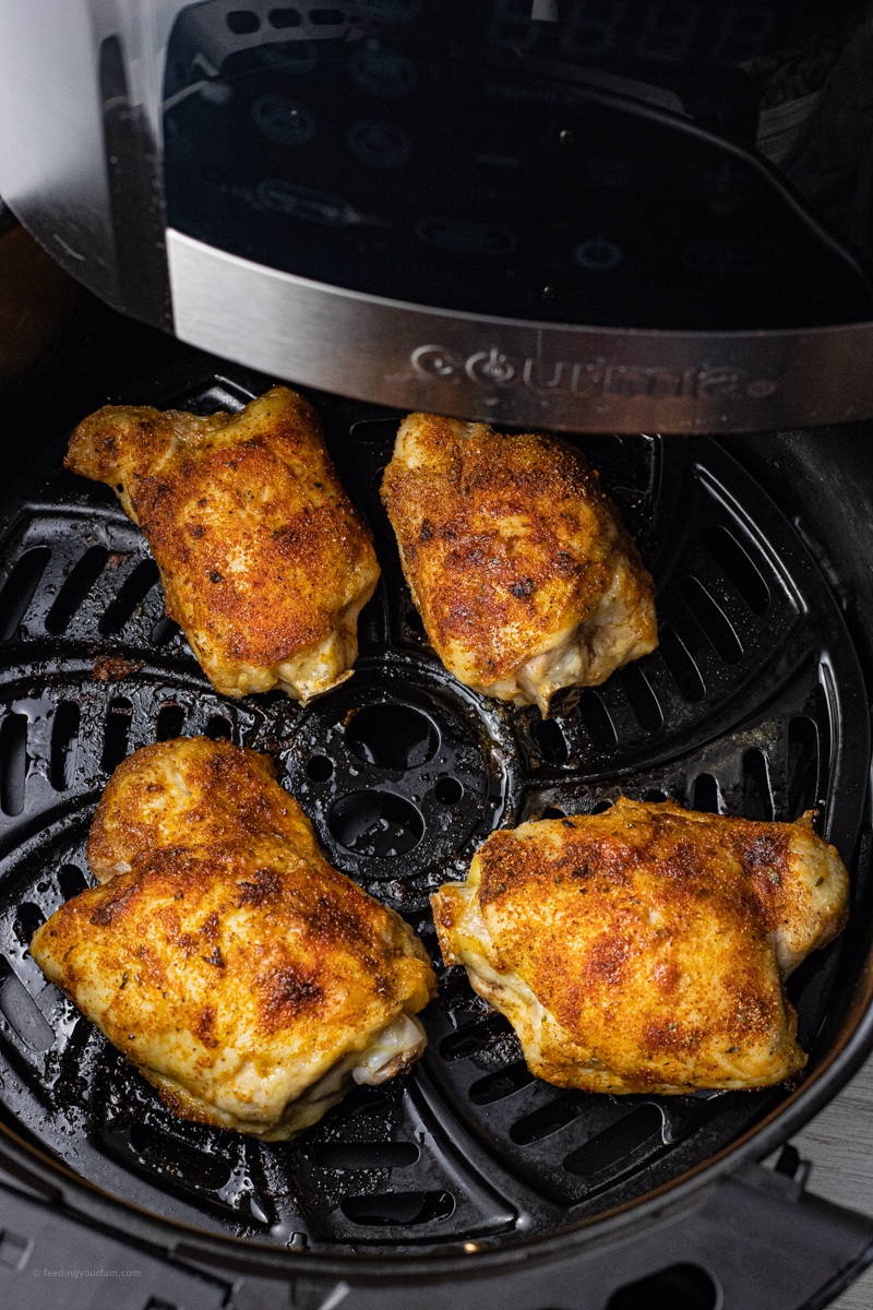 cooked chicken thighs in a black air fryer basket