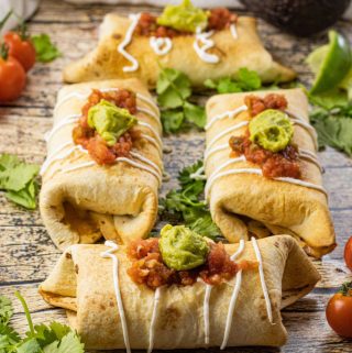 chimichangas topped with sour cream, salsa and guacamole