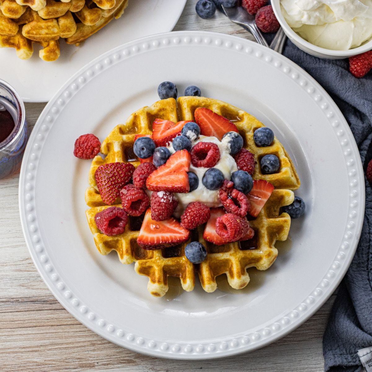 waffle topped with berries and whipped cream on a white plate