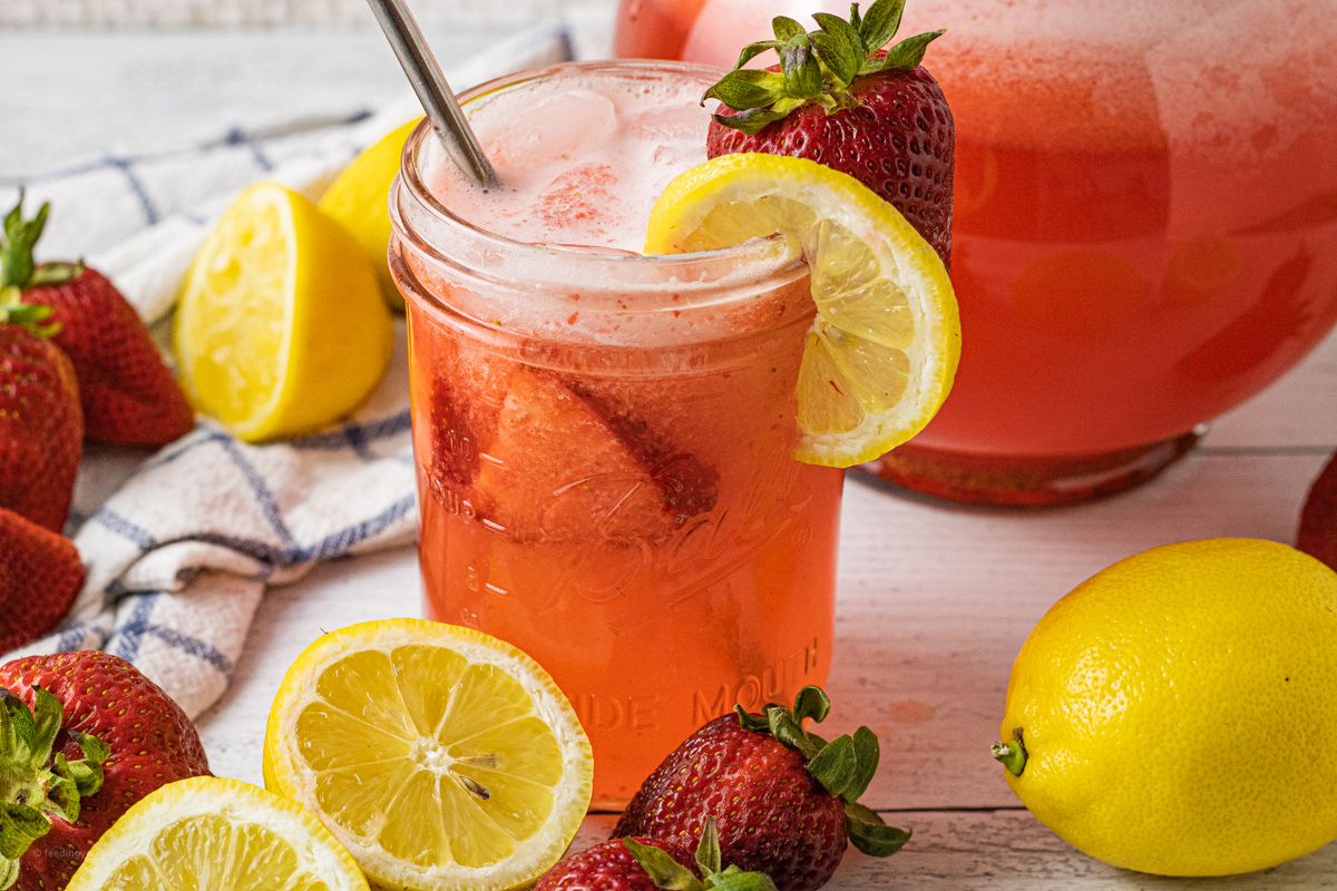 close up picture of strawberry lemonade with a lemon slice and strawberry on the edge of the cup