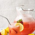 pitcher of strawberry lemonade with a jar filled with strawberry lemonade