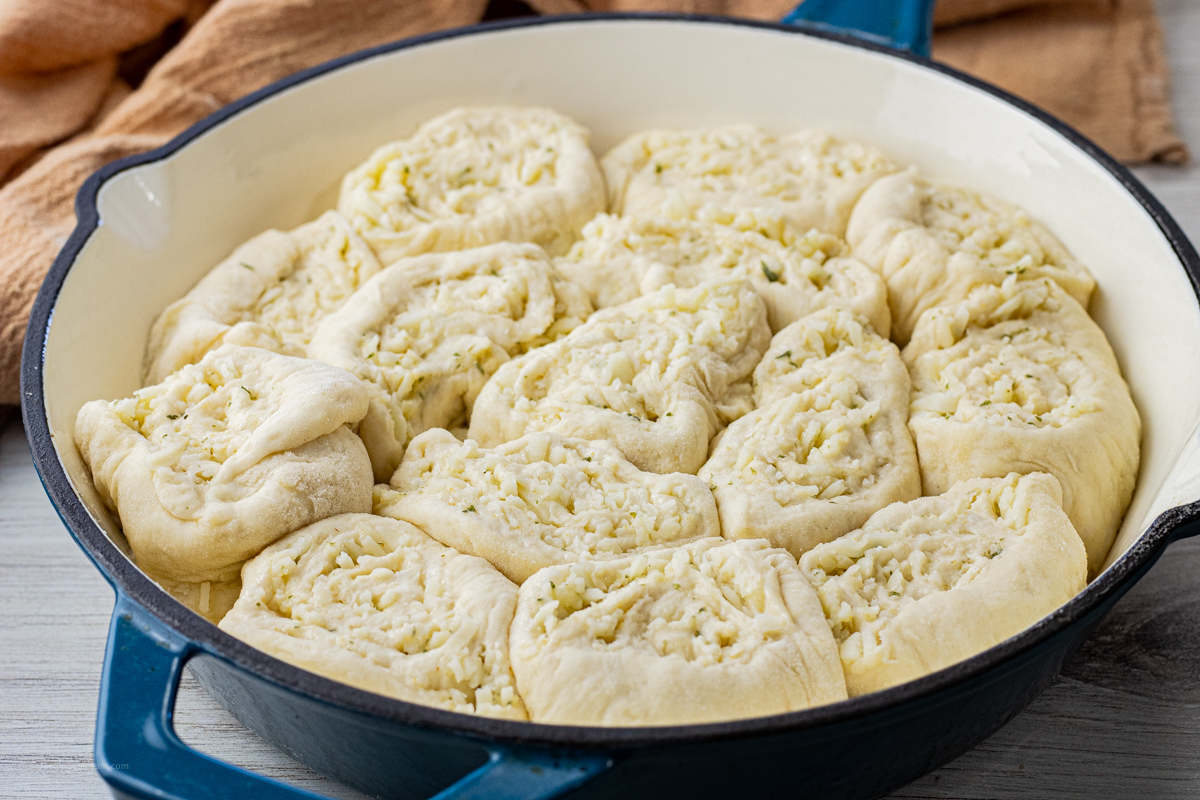 uncooked garlic cheese rolls in a cast iron pan