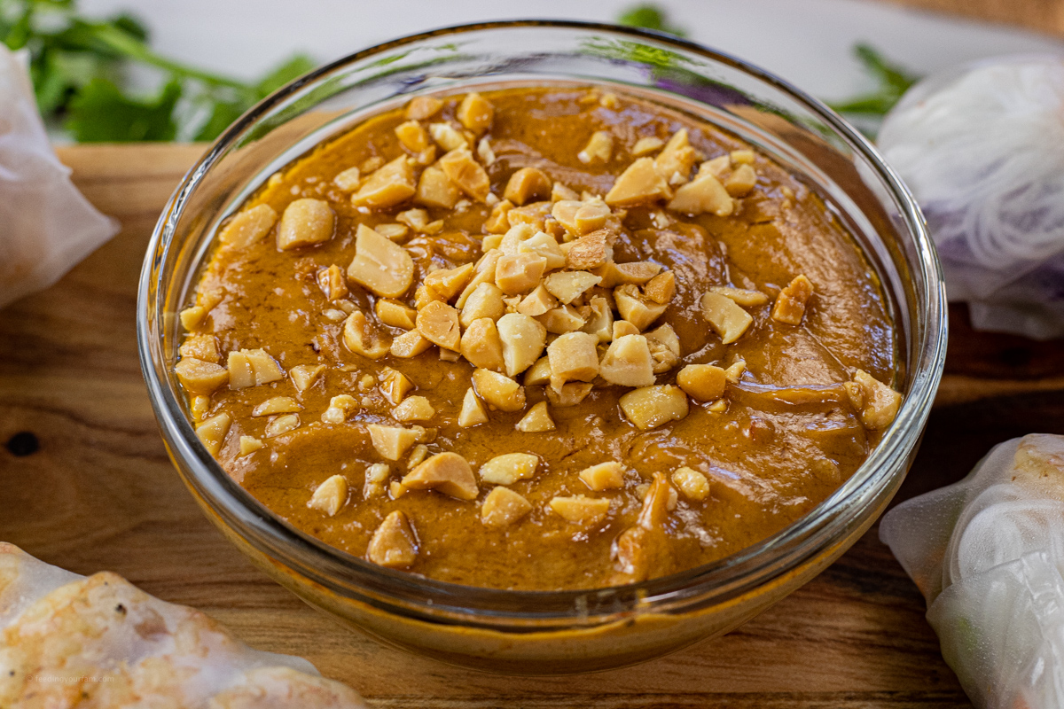bowl of peanut dipping sauce with chopped peanuts on top