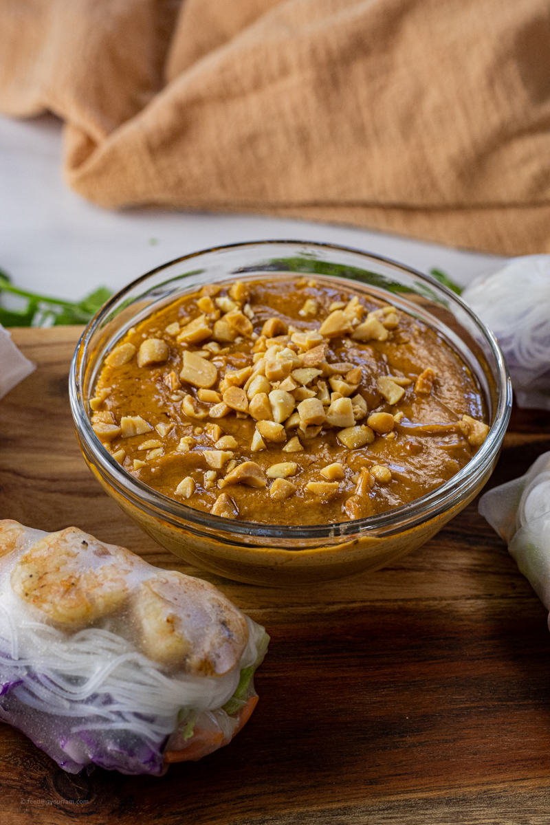 bowl of peanut butter dipping sauce topped with chopped peanuts