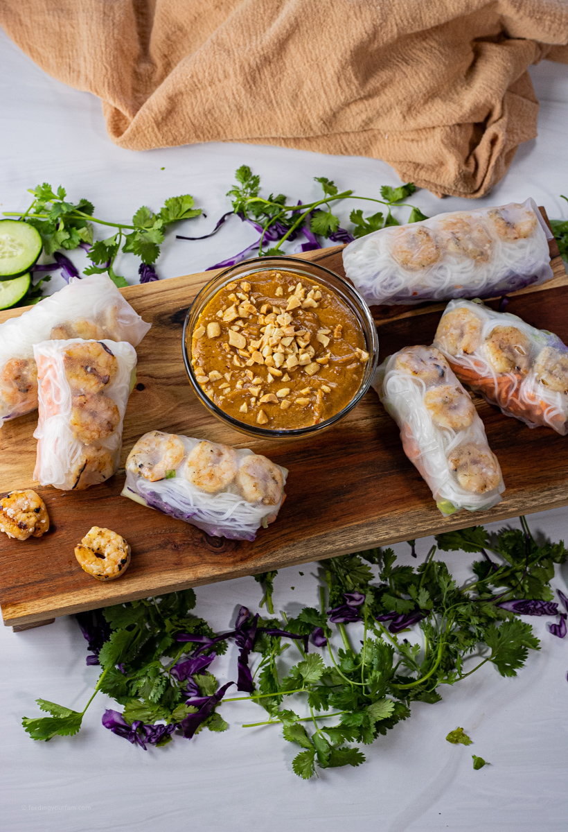 spring rolls surrounding a bowl of peanut sauce