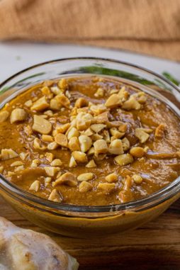 bowl of peanut sauce in a glass bowl topped with chopped peanuts
