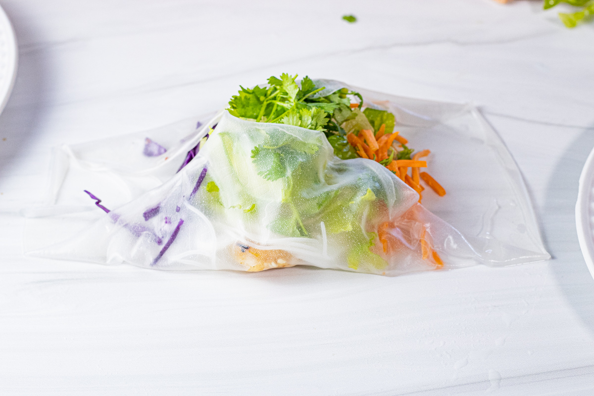 folding rice paper over ingredients to make spring roll