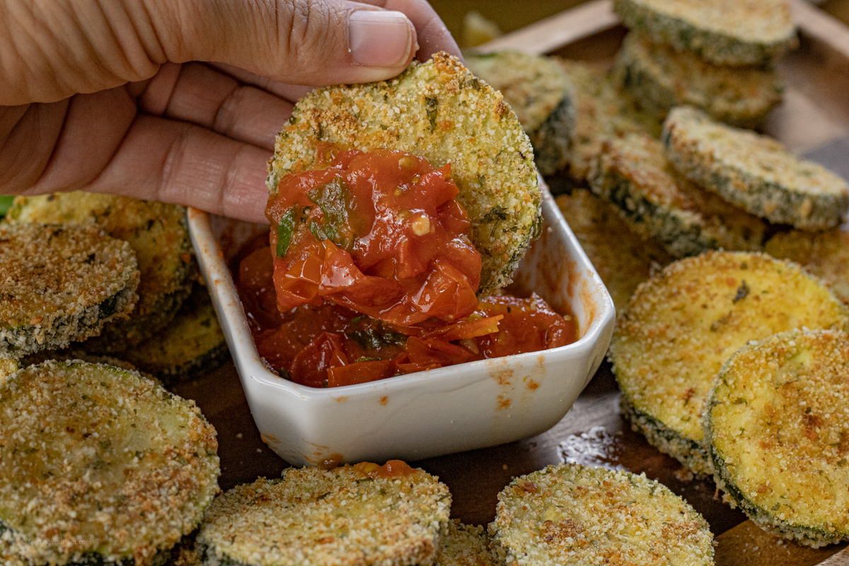 Dipping a zucchini round into a tomato basil sauce