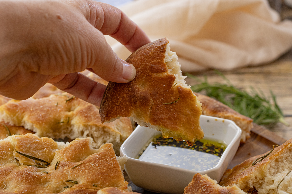 hand dipping piece of bread into olive oil