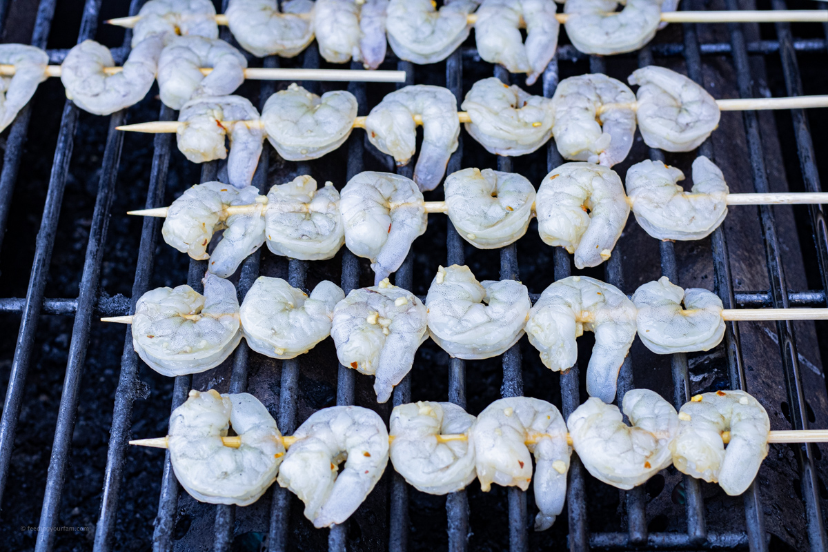 raw shrimp on skewers on grill grates