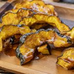 slices of cooked acorn squash on a wooden platter