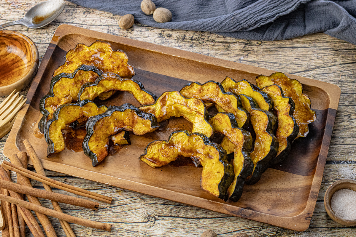 cooked slices of acorn squash on a wooden platter