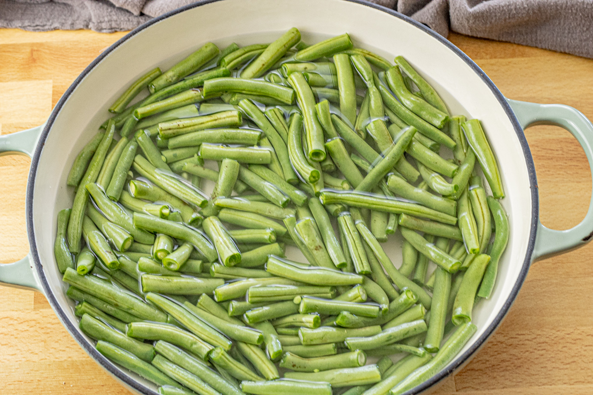 sliced green beans in water in a cast iron pan