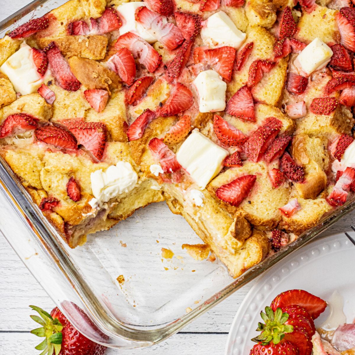 pan of strawberry cream cheese french toast with a piece missing in a glass baking dish