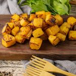 cooked cubes of butternut squash on a wooden cutting board