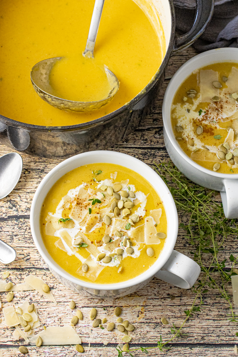 a pot and white bowl filled with butternut squash soup