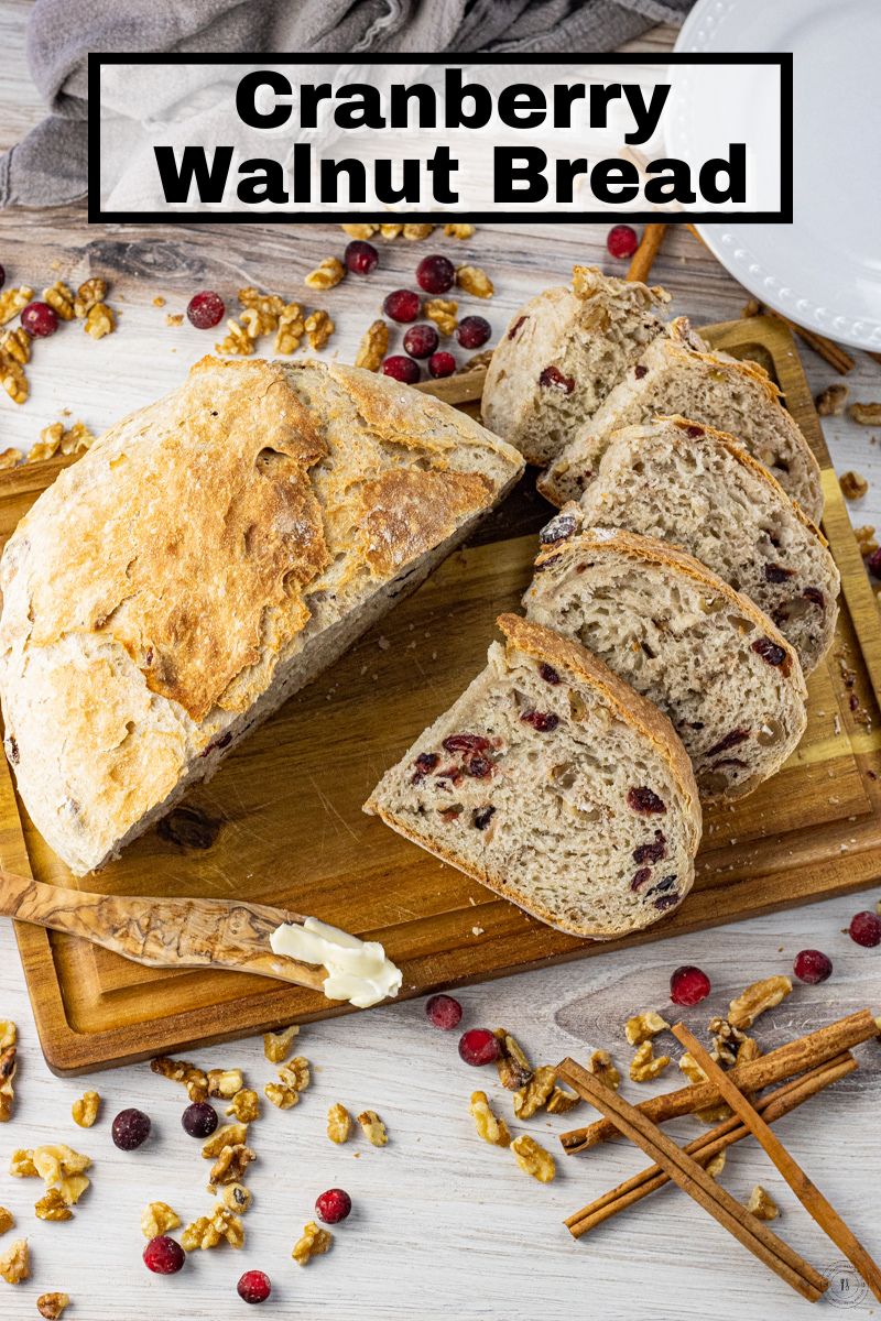 bread with cranberries and walnuts sliced on a wooden cutting board