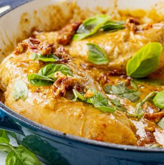 chicken in a creamy tomato sauce topped with fresh basil leaves