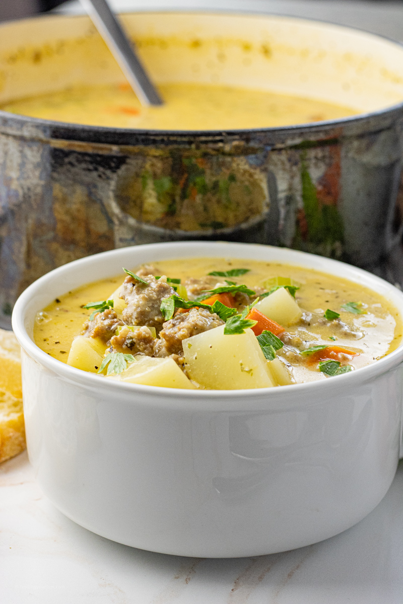 close up of potato and sausage soup in a white soup bowl
