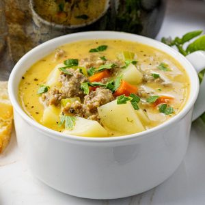 soup with potatoes and sausage in a white soup bowl